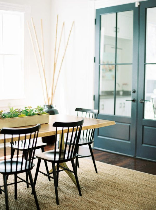 Dining room with wooden table black chairs and blue glass pane doors showing how to paint a door step by step