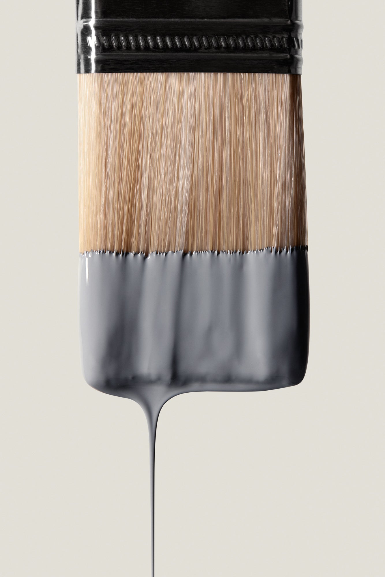 Close-up of paintbrush dripping gray dreamy interior paint by Blū Paint on light background