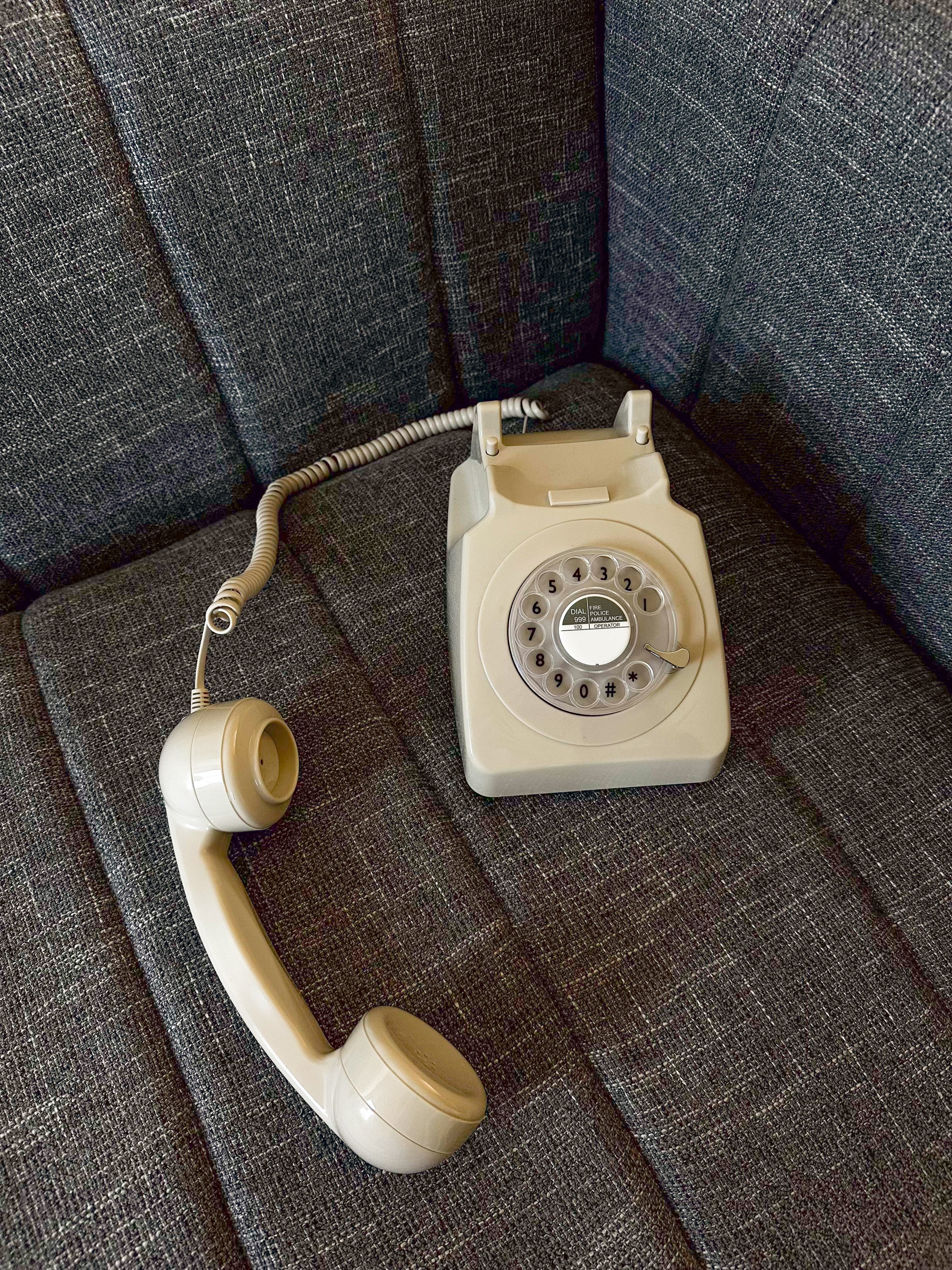 Vintage beige rotary phone on a textured gray surface